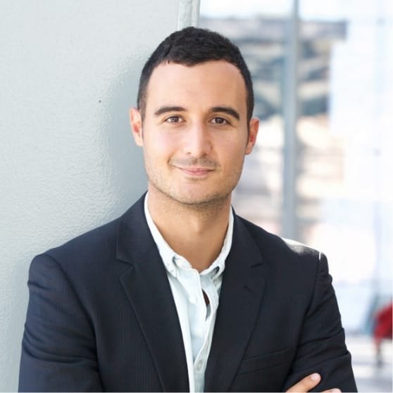 Portrait d'un client souriant avec un costume, posant en extérieur.