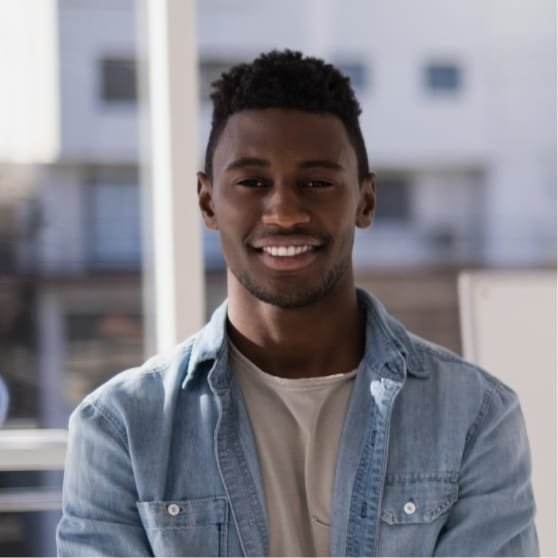 Portrait d'un jeune homme souriant en chemise en jean, posant dans un environnement lumineux